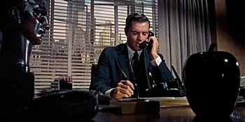 Movie still from “Imitation of Life” (1959), directed by Douglas Sirk – A man sitting at a desk talking on the phone; Medium shot, Low angle