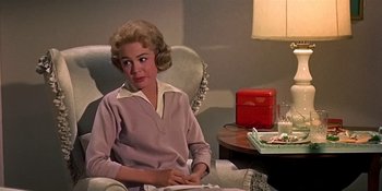 Movie still from “Imitation of Life” (1959), directed by Douglas Sirk – A woman sitting in a chair in front of a table; Medium shot, Over the shoulder angle