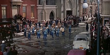 Movie still from “Imitation of Life” (1959), directed by Douglas Sirk – A parade of marching band in a city street; Extreme Wide shot, High angle