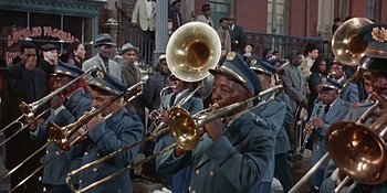 Movie still from “Imitation of Life” (1959), directed by Douglas Sirk – A group of men in uniform playing musical instruments; Wide shot, High angle