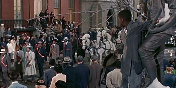 Movie still from “Imitation of Life” (1959), directed by Douglas Sirk – A crowd of people standing around a horse drawn carriage; Wide shot, High angle