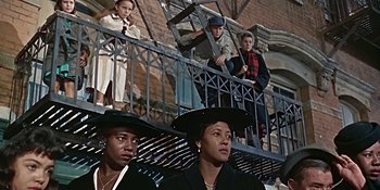 Movie still from “Imitation of Life” (1959), directed by Douglas Sirk – A group of people standing next to each other on a balcony; Medium shot, Low angle