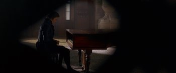 Movie still from “Immortal Beloved” (1994), directed by Bernard Rose – A man sitting in front of a piano in a dark room; Wide shot, High angle