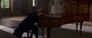 Movie still from “Immortal Beloved” (1994), directed by Bernard Rose – A man leaning on a piano in a room; Medium shot, High angle