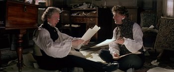 Movie still from “Immortal Beloved” (1994), directed by Bernard Rose – Two people sitting on the floor with papers in their hands; Medium shot, High angle