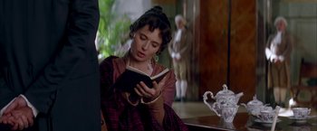 Movie still from “Immortal Beloved” (1994), directed by Bernard Rose – A woman sitting in a chair reading a book; Medium shot, Over the shoulder angle