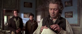 Movie still from “Immortal Beloved” (1994), directed by Bernard Rose – A man holding a pen in his hand while standing next to another man; Close Up shot, Over the shoulder angle