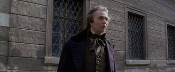 Movie still from “Immortal Beloved” (1994), directed by Bernard Rose – A man wearing a suit and bow tie standing in front of a building; Medium shot, Over the shoulder angle