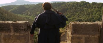 Movie still from “Immortal Beloved” (1994), directed by Bernard Rose – A man in a black coat holding an arrow; Medium shot, Over the shoulder angle