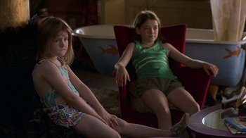 Movie still from “In America” (2002), directed by Jim Sheridan – Two young girls sitting on a chair in a living room; Medium shot, High angle