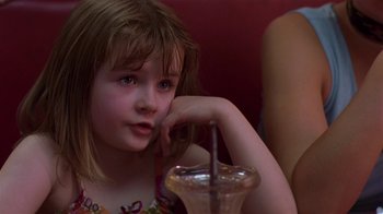 Movie still from “In America” (2002), directed by Jim Sheridan – A little girl sitting in front of a drink; Close Up shot, Over the shoulder angle