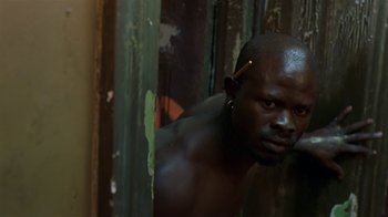 Movie still from “In America” (2002), directed by Jim Sheridan – A man with a beard and a nose ring is leaning against a wall; Close Up shot, Low angle