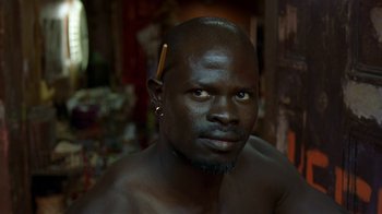 Movie still from “In America” (2002), directed by Jim Sheridan – A man with a shaved head and a piercing in his ear; Close Up shot, High angle