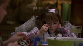 Movie still from “In America” (2002), directed by Jim Sheridan – A little girl wearing a silver crown while putting makeup on her face; Close Up shot, High angle