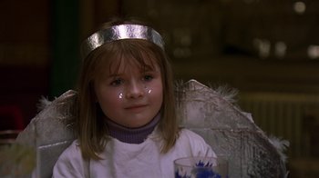 Movie still from “In America” (2002), directed by Jim Sheridan – A little girl wearing a silver crown sitting in a chair; Close Up shot, High angle