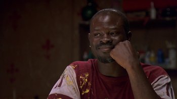 Movie still from “In America” (2002), directed by Jim Sheridan – A man with a beard is sitting with his chin resting on his hand; Close Up shot, Over the shoulder angle