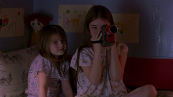 Movie still from “In America” (2002), directed by Jim Sheridan – Two young girls are taking a picture with a camera; Medium shot, High angle