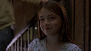 Movie still from “In America” (2002), directed by Jim Sheridan – A young girl smiling for the camera in front of a railing; Close Up shot, Over the shoulder angle