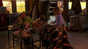 Movie still from “In America” (2002), directed by Jim Sheridan – A man and a woman sitting on a chair in a room; Wide shot, High angle