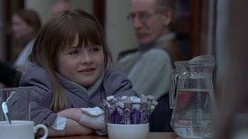 Movie still from “In America” (2002), directed by Jim Sheridan – A young girl sitting at a table with a pitcher of water; Close Up shot, Over the shoulder angle
