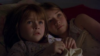 Movie still from “In America” (2002), directed by Jim Sheridan – Two young girls sitting next to each other on a bed; Close Up shot, High angle