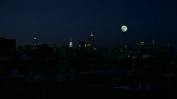 Movie still from “In America” (2002), directed by Jim Sheridan – A full moon rises over a city at night; Extreme Wide shot, Low angle
