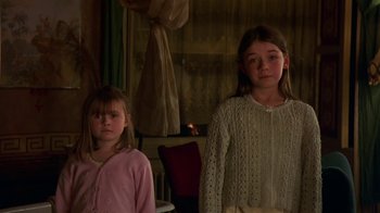 Movie still from “In America” (2002), directed by Jim Sheridan – Two young girls standing next to each other in front of a fireplace; Medium shot, Low angle