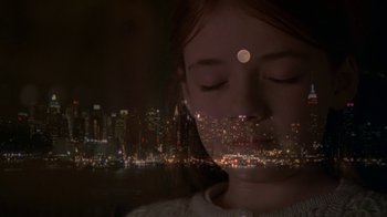 Movie still from “In America” (2002), directed by Jim Sheridan – A woman with her eyes closed in front of a city skyline at night; Close Up shot, High angle