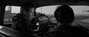 Movie still from “In Cold Blood” (1967), directed by Richard Brooks – Two men in a car one is driving and the other is looking out the window; Medium shot, Over the shoulder angle