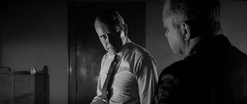 Movie still from “In Cold Blood” (1967), directed by Richard Brooks – A black and white photo of a man wearing a tie; Medium shot, Over the shoulder angle