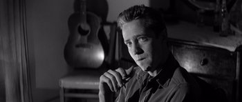 Movie still from “In Cold Blood” (1967), directed by Richard Brooks – Black and white photograph of a man with a guitar in the background; Close Up shot, Low angle