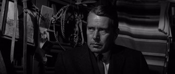 Movie still from “In Cold Blood” (1967), directed by Richard Brooks – A man wearing a suit and tie in front of ropes; Close Up shot, Over the shoulder angle