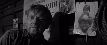 Movie still from “In Cold Blood” (1967), directed by Richard Brooks – Black and white photograph of a man in front of pictures; Close Up shot, Over the shoulder angle