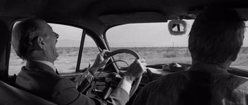 Movie still from “In Cold Blood” (1967), directed by Richard Brooks – An older man driving a car in the desert; Close Up shot, Over the shoulder angle
