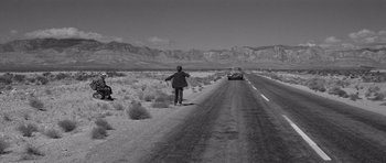 Movie still from “In Cold Blood” (1967), directed by Richard Brooks – A man standing on the side of a road near a car; Extreme Wide shot, High angle