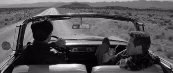 Movie still from “In Cold Blood” (1967), directed by Richard Brooks – A man driving a car on a dirt road; Wide shot, High angle