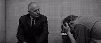 Movie still from “In Cold Blood” (1967), directed by Richard Brooks – An older man in a suit and tie talking to a young man; Medium shot, Over the shoulder angle