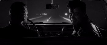 Movie still from “In Cold Blood” (1967), directed by Richard Brooks – A black and white photo of a man in the driver's seat of a car at night; Close Up shot, Over the shoulder angle