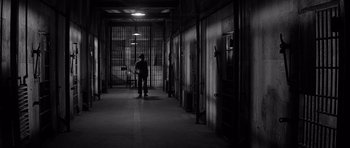 Movie still from “In Cold Blood” (1967), directed by Richard Brooks – A person standing in a dark room next to a door way; Wide shot, High angle
