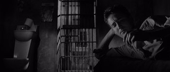 Movie still from “In Cold Blood” (1967), directed by Richard Brooks – A man leaning against a wall in front of a jail cell; Close Up shot, Low angle