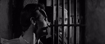 Movie still from “In Cold Blood” (1967), directed by Richard Brooks – A man in a jail cell with another man behind bars; Close Up shot, Low angle