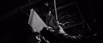 Movie still from “In Cold Blood” (1967), directed by Richard Brooks – A man in a suit and a hat is holding a rope; Medium shot, Low angle