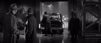 Movie still from “In Cold Blood” (1967), directed by Richard Brooks – A man standing in front of a truck in the rain; Wide shot, Low angle