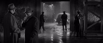Movie still from “In Cold Blood” (1967), directed by Richard Brooks – A group of men standing in front of an open door; Wide shot, Over the shoulder angle