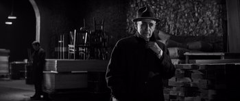 Movie still from “In Cold Blood” (1967), directed by Richard Brooks – An older man wearing a hat standing in front of a chair; Medium shot, Low angle