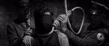 Movie still from “In Cold Blood” (1967), directed by Richard Brooks – A man in a black mask is tied to a rope; Close Up shot, Over the shoulder angle