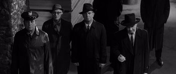 Movie still from “In Cold Blood” (1967), directed by Richard Brooks – A black and white photo of a group of men in suits and hats; Medium shot, High angle