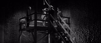 Movie still from “In Cold Blood” (1967), directed by Richard Brooks – A group of men standing on top of a set of stairs; Wide shot, Low angle