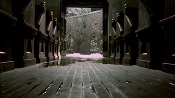 Movie still from “In Dreams” (1999), directed by Neil Jordan – An open door leading into a building with a tree in the background; Wide shot, High angle