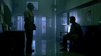 Movie still from “In Dreams” (1999), directed by Neil Jordan – Two men are standing in a dark room talking; Wide shot, Low angle